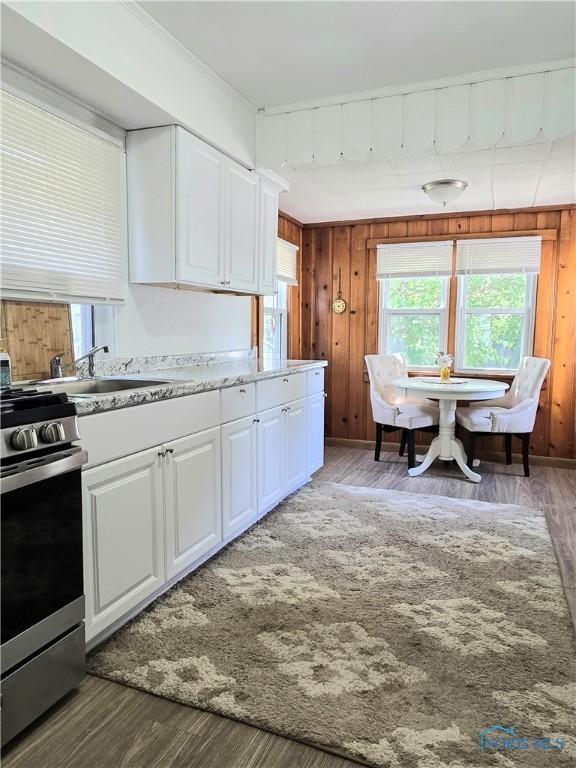1723 Balkan Pl, Toledo, OH 43613 - kitchen with stainless steel gas range, white cabinetry, wood finished floors, and wooden walls