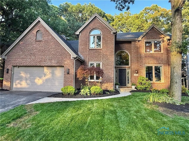 2456 Wembley Ter, Toledo, OH 43617 - traditional-style house featuring driveway, a front lawn, brick siding, and a garage