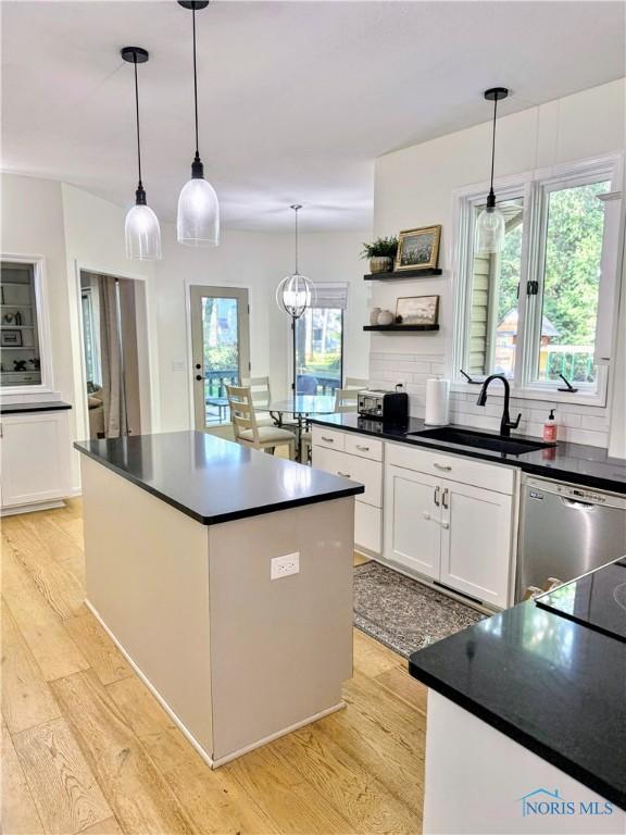 2456 Wembley Ter, Toledo, OH 43617 - kitchen with stainless steel dishwasher, open shelves, dark countertops, light wood-style floors, and white cabinetry