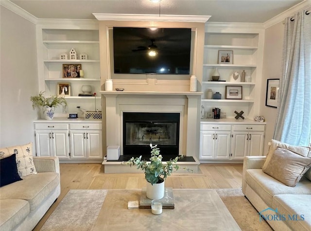 2456 Wembley Ter, Toledo, OH 43617 - living area featuring light wood finished floors, a glass covered fireplace, crown molding, and built in shelves
