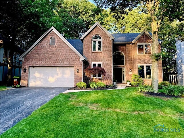 2456 Wembley Ter, Toledo, OH 43617 - traditional home with driveway, a front yard, an attached garage, and brick siding
