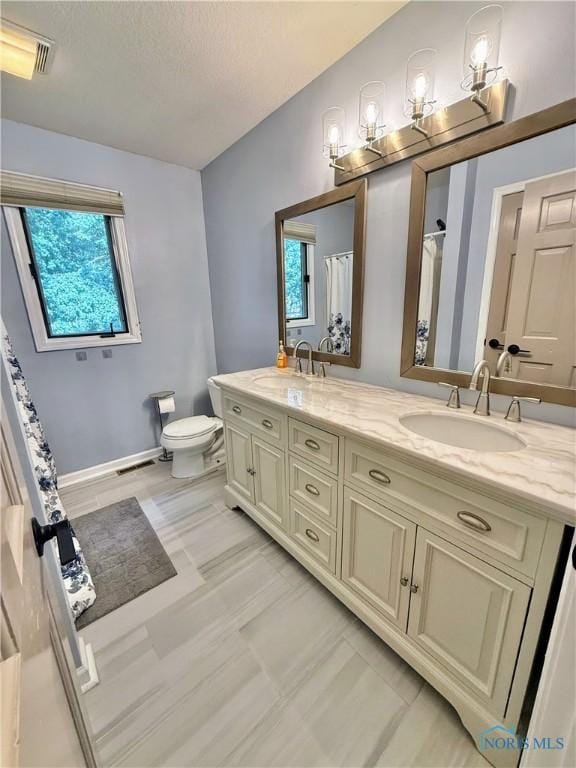2456 Wembley Ter, Toledo, OH 43617 - full bath featuring double vanity, plenty of natural light, a textured ceiling, and curtained shower