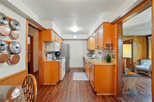 2519 Melva Ct, Toledo, OH 43611 - kitchen with white appliances, wood walls, light countertops, dark wood-style floors, and backsplash
