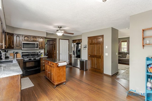 5226 Summer Dr, Sylvania, OH 43560 - kitchen with appliances with stainless steel finishes, dark wood-type flooring, a ceiling fan, a kitchen island, and a textured ceiling