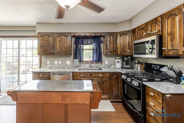 5226 Summer Dr, Sylvania, OH 43560 - kitchen featuring appliances with stainless steel finishes, dark wood finished floors, a center island, a ceiling fan, and dark brown cabinetry