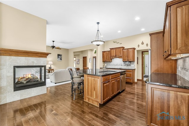 4068 Deer Ravine Ct, Maumee, OH 43537 - kitchen with dishwasher, dark wood-type flooring, brown cabinetry, a breakfast bar area, and a ceiling fan