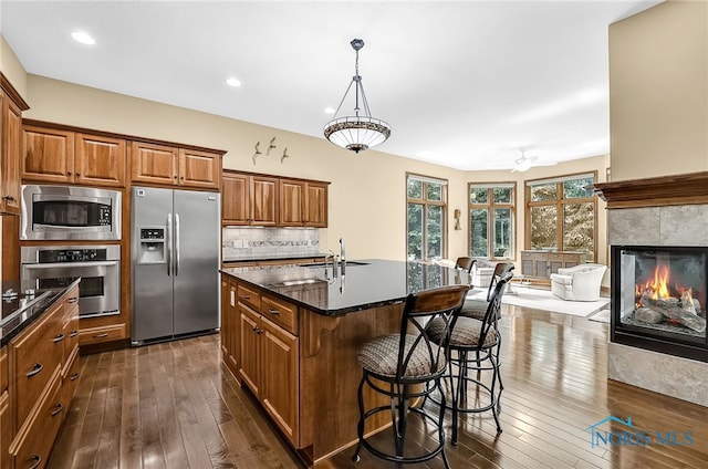 4068 Deer Ravine Ct, Maumee, OH 43537 - kitchen with appliances with stainless steel finishes, brown cabinetry, dark wood-style floors, a kitchen breakfast bar, and a kitchen island with sink