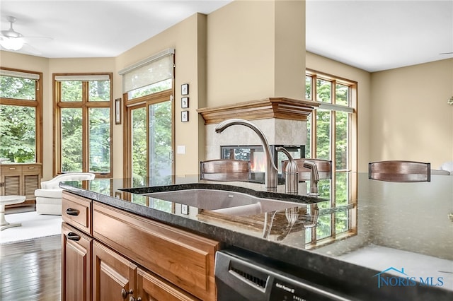 4068 Deer Ravine Ct, Maumee, OH 43537 - kitchen with brown cabinetry, dark stone countertops, wood finished floors, and a ceiling fan