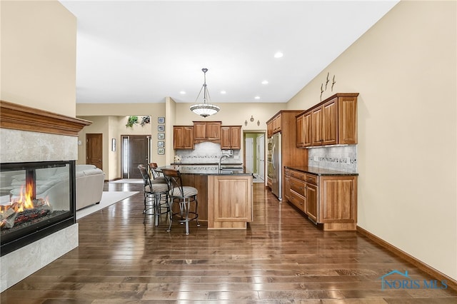 4068 Deer Ravine Ct, Maumee, OH 43537 - kitchen with freestanding refrigerator, dark countertops, dark wood-type flooring, a kitchen bar, and backsplash