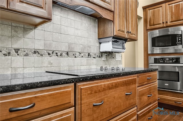 4068 Deer Ravine Ct, Maumee, OH 43537 - kitchen with appliances with stainless steel finishes, tasteful backsplash, premium range hood, dark stone countertops, and brown cabinetry