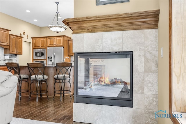 4068 Deer Ravine Ct, Maumee, OH 43537 - kitchen with refrigerator with ice dispenser, stainless steel microwave, a kitchen bar, dark wood-style floors, and brown cabinetry