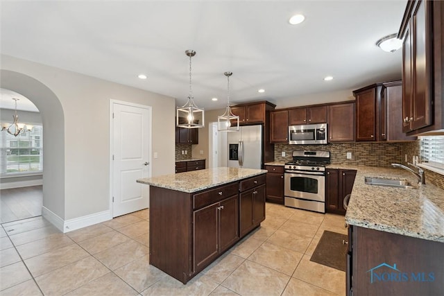 4382 Morgan Pl, Perrysburg, OH 43551 - kitchen with stainless steel appliances, arched walkways, dark brown cabinets, decorative backsplash, and light tile patterned floors