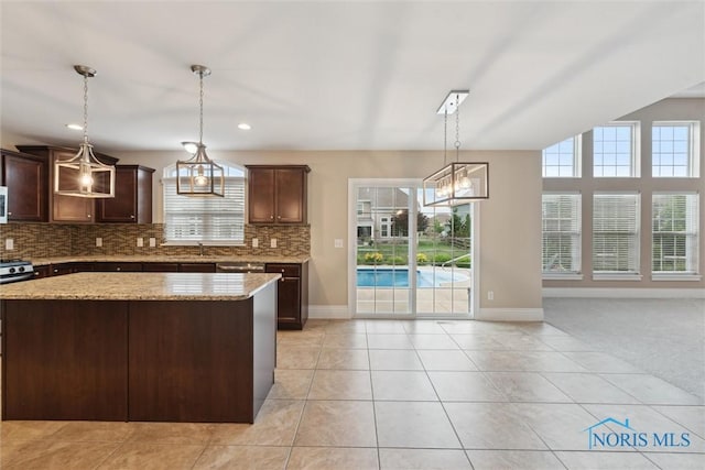 4382 Morgan Pl, Perrysburg, OH 43551 - kitchen with tasteful backsplash, dark brown cabinets, light stone countertops, light tile patterned floors, and a center island