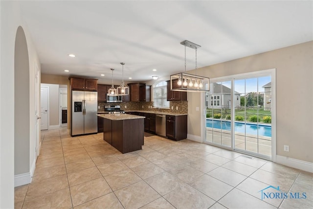 4382 Morgan Pl, Perrysburg, OH 43551 - kitchen featuring stainless steel appliances, tasteful backsplash, dark brown cabinetry, light tile patterned flooring, and a kitchen island