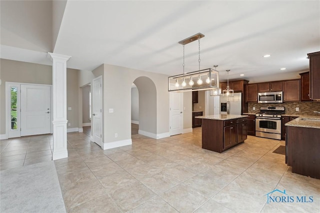 4382 Morgan Pl, Perrysburg, OH 43551 - kitchen featuring stainless steel appliances, a kitchen island, tasteful backsplash, dark brown cabinetry, and decorative light fixtures