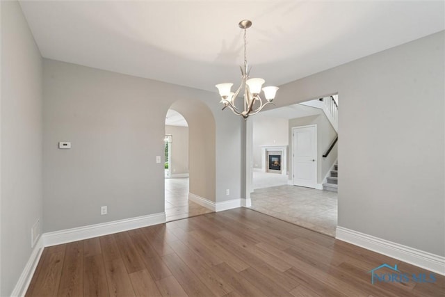 4382 Morgan Pl, Perrysburg, OH 43551 - empty room featuring arched walkways, wood finished floors, a chandelier, and stairway