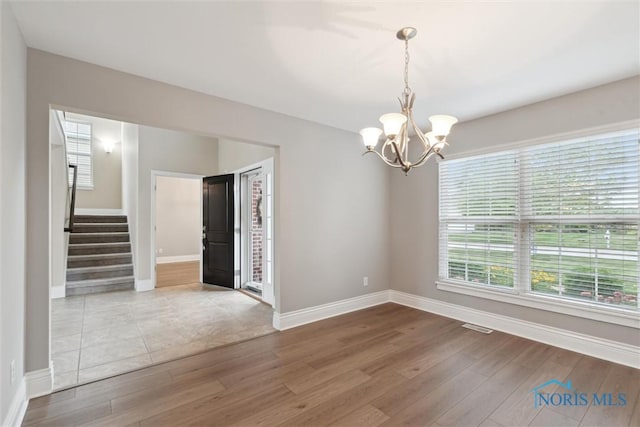 4382 Morgan Pl, Perrysburg, OH 43551 - empty room with a chandelier, wood finished floors, stairway, and healthy amount of natural light