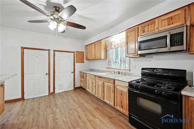 356 S Belmore St, Leipsic, OH 45856 - kitchen with black range with gas stovetop, stainless steel microwave, ceiling fan, light countertops, and light wood-style floors