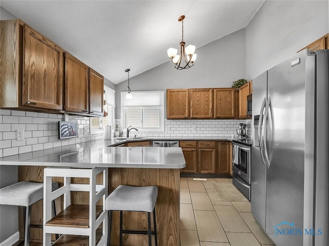 5425 Tulane Ave, Toledo, OH 43611 - kitchen featuring appliances with stainless steel finishes, a peninsula, vaulted ceiling, brown cabinetry, and backsplash