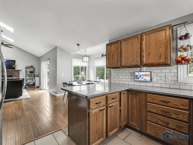 5425 Tulane Ave, Toledo, OH 43611 - kitchen with a peninsula, brown cabinets, decorative backsplash, open floor plan, and light countertops