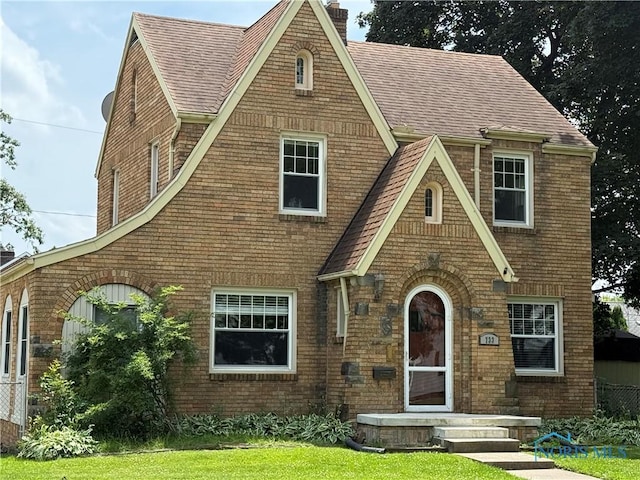 733 Mayfair Blvd, Toledo, OH 43612 - tudor-style house with a chimney, roof with shingles, and brick siding