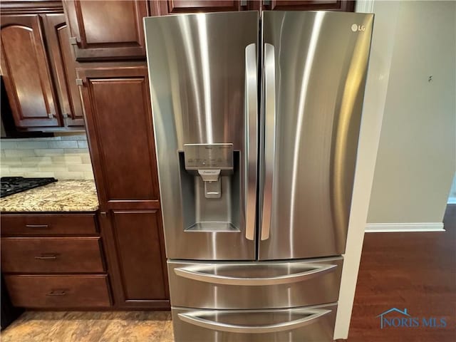 5346 Palisades Dr, Sylvania, OH 43560 - kitchen view of stainless steel refrigerator with ice dispenser, light stone counters, backsplash, and light wood finished floors