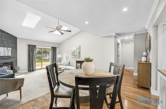 11 Meadowpond Dr, Perrysburg, OH 43551 - dining space featuring a skylight, ceiling fan, light wood finished floors, crown molding, and a fireplace