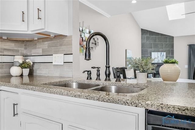 11 Meadowpond Dr, Perrysburg, OH 43551 - kitchen with white cabinets, vaulted ceiling, dishwasher, light stone counters, and a skylight