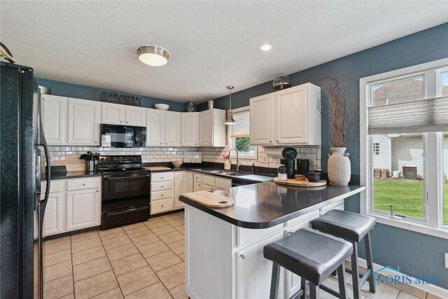 735 Hemlock St, Wauseon, OH 43567 - kitchen featuring black appliances, a peninsula, decorative backsplash, healthy amount of natural light, and recessed lighting
