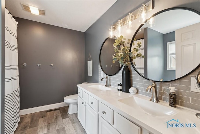 735 Hemlock St, Wauseon, OH 43567 - bathroom with double vanity, tasteful backsplash, and wood finished floors