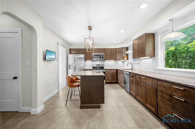 2230 Middlesex Dr, Toledo, OH 43606 - kitchen featuring appliances with stainless steel finishes, open shelves, backsplash, a kitchen bar, and hanging light fixtures