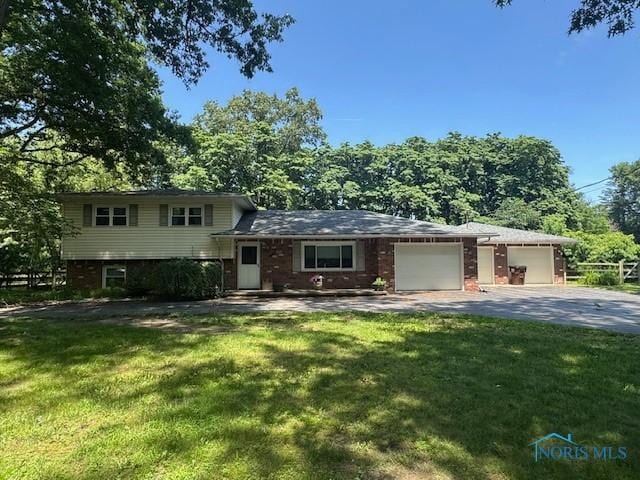 7948 Holstein Rd, Toledo, OH 43617 - split level home with a front lawn, a garage, driveway, and brick siding