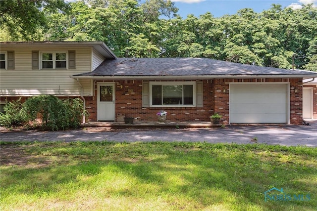 7948 Holstein Rd, Toledo, OH 43617 - tri-level home with brick siding, an attached garage, asphalt driveway, and a front yard