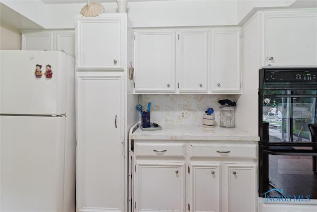 7948 Holstein Rd, Toledo, OH 43617 - kitchen featuring freestanding refrigerator, white cabinetry, light countertops, and decorative backsplash