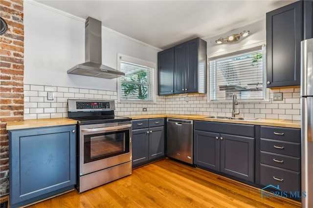 1022 E Sandusky St, Findlay, OH 45840 - kitchen featuring wall chimney exhaust hood, appliances with stainless steel finishes, wood counters, crown molding, and light wood finished floors