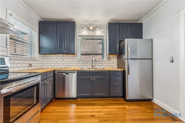 1022 E Sandusky St, Findlay, OH 45840 - kitchen with appliances with stainless steel finishes, backsplash, healthy amount of natural light, crown molding, and light wood-type flooring