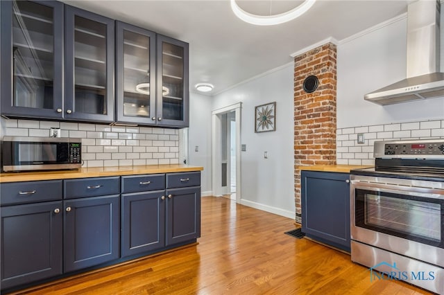 1022 E Sandusky St, Findlay, OH 45840 - kitchen featuring wall chimney exhaust hood, appliances with stainless steel finishes, butcher block countertops, blue cabinets, and crown molding