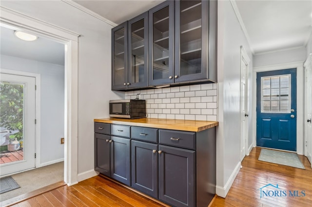 1022 E Sandusky St, Findlay, OH 45840 - bar area featuring stainless steel microwave, dark wood-style floors, decorative backsplash, and ornamental molding