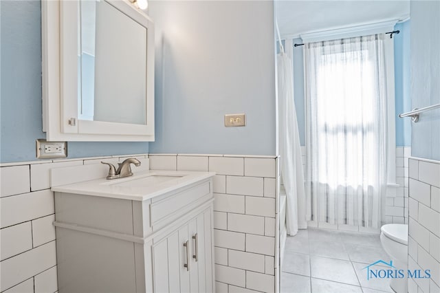 1022 E Sandusky St, Findlay, OH 45840 - bathroom with tile walls, a wainscoted wall, vanity, tile patterned flooring, and shower / bathtub combination with curtain