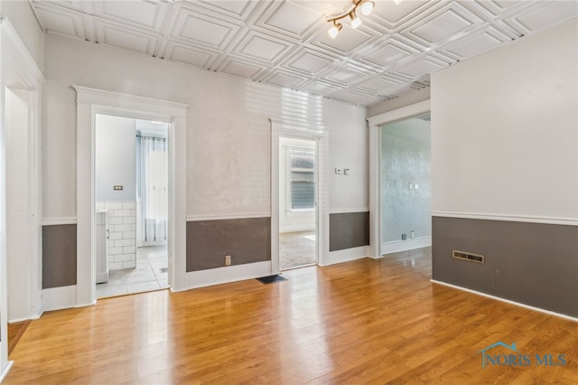 1022 E Sandusky St, Findlay, OH 45840 - spare room featuring light wood-style floors, a wainscoted wall, and an ornate ceiling
