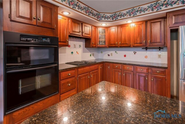 5301 River Oaks Ct, Sylvania, OH 43560 - kitchen with stovetop with downdraft, freestanding refrigerator, decorative backsplash, dark stone countertops, and brown cabinets