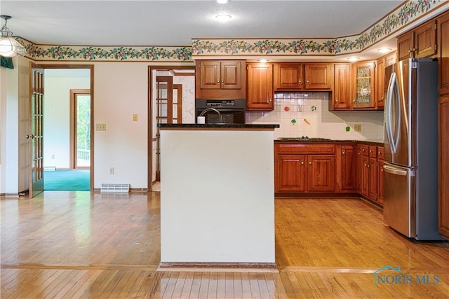 5301 River Oaks Ct, Sylvania, OH 43560 - kitchen featuring appliances with stainless steel finishes, light wood-type flooring, brown cabinetry, and decorative backsplash