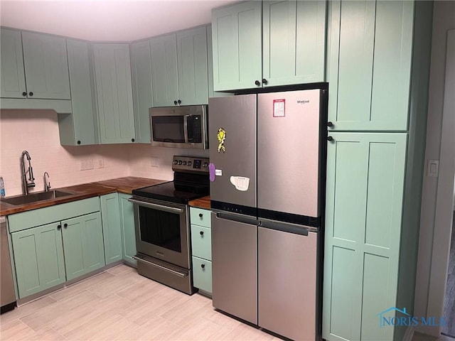 611 Greenfield Dr, Maumee, OH 43537 - kitchen featuring stainless steel appliances, green cabinetry, wood counters, and decorative backsplash
