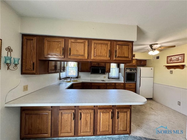 410 E Bartlow St, Deshler, OH 43516 - kitchen with black appliances, a peninsula, light countertops, a ceiling fan, and brown cabinetry