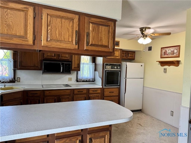 410 E Bartlow St, Deshler, OH 43516 - kitchen featuring black appliances, ceiling fan, light colored carpet, brown cabinetry, and light countertops