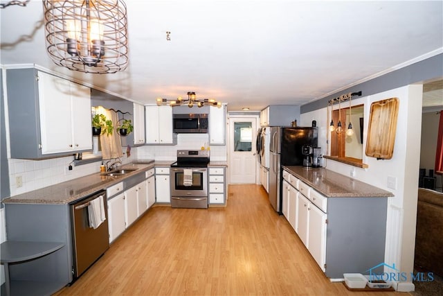 317 E Rosewood Ave, Defiance, OH 43512 - kitchen with appliances with stainless steel finishes, a chandelier, light wood finished floors, backsplash, and crown molding