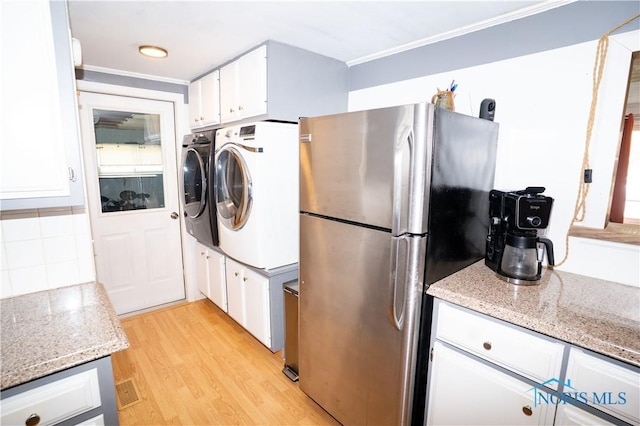 317 E Rosewood Ave, Defiance, OH 43512 - kitchen with freestanding refrigerator, washing machine and clothes dryer, white cabinetry, ornamental molding, and light wood-style floors