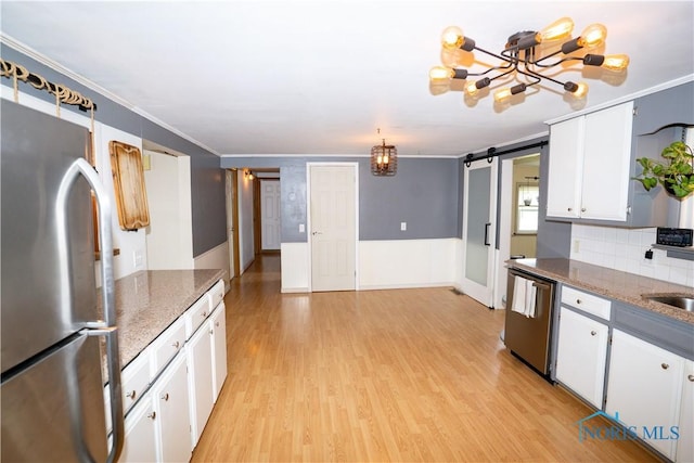 317 E Rosewood Ave, Defiance, OH 43512 - kitchen with stainless steel appliances, light wood-style floors, white cabinets, a barn door, and crown molding