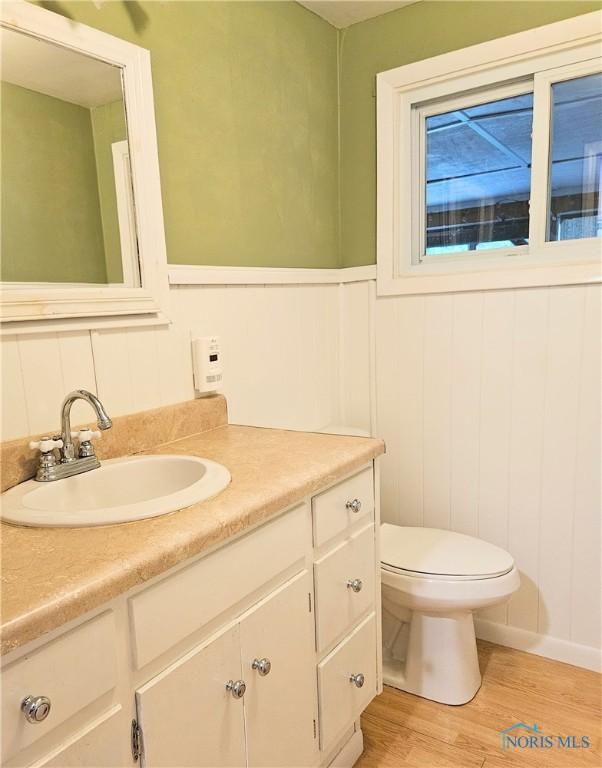 317 E Rosewood Ave, Defiance, OH 43512 - half bath featuring vanity, wood finished floors, wainscoting, and a decorative wall
