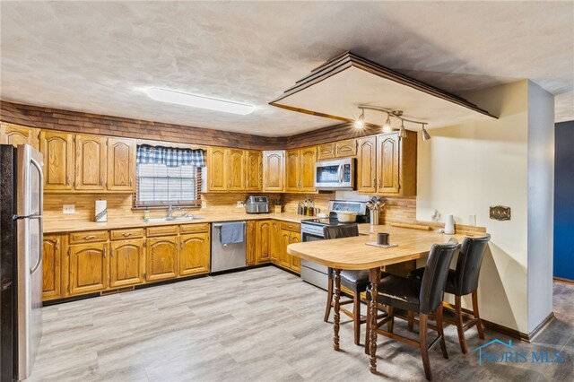 807 S Jefferson St, Pandora, OH 45877 - kitchen with appliances with stainless steel finishes, light countertops, brown cabinets, tasteful backsplash, and light wood-type flooring